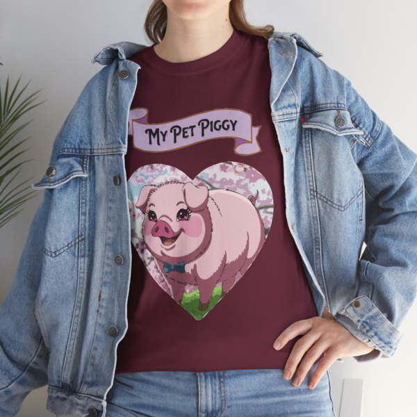 3316995964716954883_2048.webp A woman wearing a burgundy t-shirt with a cartoon pig design inside a heart shape, reading 'My Pet Piggy'.