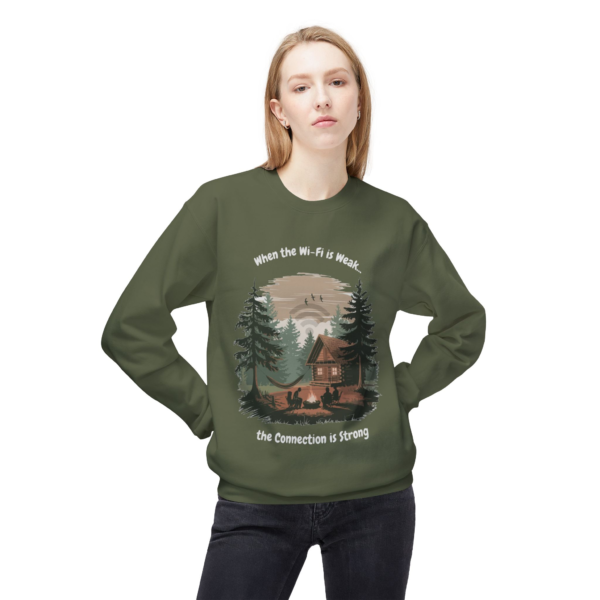 4185759006085662335_2048.webp Woman wearing a green sweatshirt featuring a cabin scene with the text 'When the Wi-Fi is Weak...the Connection is Strong'.