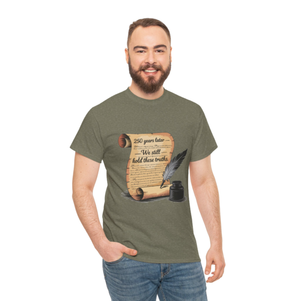 4674481313687097162_2048.webp A man smiles while wearing a heather green t-shirt featuring a graphic of a scroll that reads, "250 years later - We still hold these truths," along with a quill pen and inkwell.