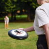 6638853974647540460_2048.webp A woman holds a black frisbee with an eagle and American flag design, commemorating 250 years of freedom from 1776-2026.